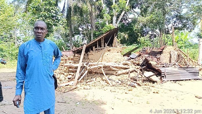 Village Head of Ukim Ita Eyo Ndem Community, Chief Samuel Ekpe-Ita, standing in front of the murder suspect's (Akaniyene Ignatius Eshiet), a destroyed property Village Head of Ukim Ita Eyo Ndem Community, Chief Samuel Ekpe-Ita, standing in front of the murder suspect's (Akaniyene Ignatius Eshiet), a destroyed property